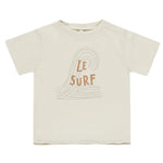 The Rylee & Cru Baby Boys' and Boys' Raw Edge Tee features soft beige cotton slub fabric, a simple wave line drawing, and “Le Surf” printed on the front in brown letters.