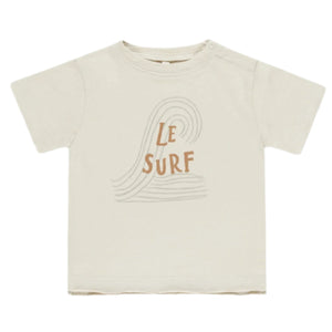 The Rylee & Cru Baby Boys' and Boys' Raw Edge Tee features soft beige cotton slub fabric, a simple wave line drawing, and “Le Surf” printed on the front in brown letters.
