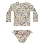 The Rylee & Cru Baby Girls' and Girl's Maryn Rashguard Set features a blue and brown floral print on off-white, with long sleeves, matching bikini bottoms, and UPF 50+ protection, shown laid flat on a white surface.