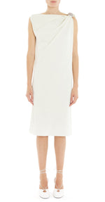 A woman faces forward wearing the Lanvin Arpège Ring Draped Dress, a sleeveless white silk knee-length piece with one-shoulder draping, paired with white lace-up shoes for an elegant silhouette.
