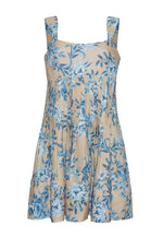 The Cara Cara Ria Dress is a sleeveless beige dress with wide straps, blue floral print, pintucked details, a loose gathered skirt, and a square neckline for a picture-perfect look.