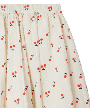 Close-up of the Girls' Suzon Skirt with Cherry Print by Bonpoint, featuring a cream color, gathered waistband, and a charming pattern of small red cherries with black stems.