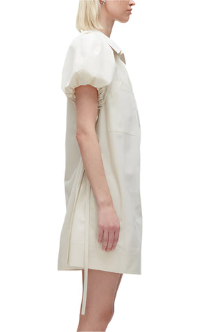 Someone is shown in a side profile wearing the Puff Sleeve Short Shirt Dress by 3.1 Phillip Lim, featuring off-white signature technical poplin with short sleeves, a collar, and a side tie.