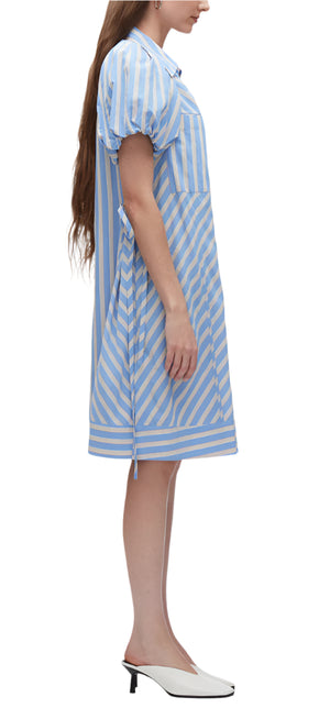 A person models the Puff Sleeve Stripe Short Shirt Dress by 3.1 Phillip Lim, featuring blue and white stripes and puff lantern sleeves in technical poplin, elegantly paired with white heeled shoes.