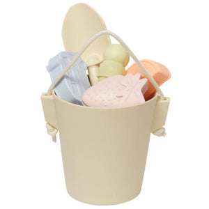 The Sunnylife Silicone Bucket & Spade Set Apple Sorbet Multi features pastel beach toys—a spade set, spoon, shovel, and molds—ideal for sandcastle building, all in a beige silicone bucket against a white background.