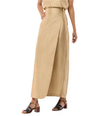A person wears the Ann Mashburn Renata Silk Shantung Wrap Skirt in beige, styled with a matching top and black heeled sandals; their face is not visible.