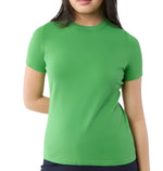 A person wears the Ann Mashburn Lee Tee, a plain green luxury t-shirt with a body-hugging fit, paired with dark pants and standing against a white background.