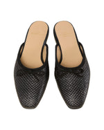 The Joy Basketweave Mule by Ann Mashburn features black woven mules with an almond-shaped toe box, a small bow on each shoe, a low heel, and a tan insole. Crafted in Italy for optimal craftsmanship.