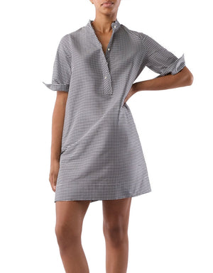 A person is wearing the Ann Mashburn Elbow Sleeve Frill Dress, featuring black and white checks and a feminine popover style, standing against a plain white background.