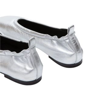 Close-up of two metallic-silver ID Stretch Back Ballet Flats by 3.1 Phillip Lim, featuring elasticized edges and black soles, elegantly positioned with heels facing the viewer.