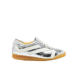 The Proenza Schouler Track Crinkled Metallic Sneakers feature silver metallic leather with white accents and laces, plus a light brown rubber sole, shown in profile against a white background.