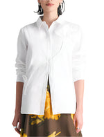 A woman stands facing forward wearing the Lela Rose Draped Rose Button Down Shirt, a long-sleeved cotton poplin shirt, paired with a brown skirt featuring a yellow floral pattern.