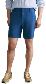 Person in a striped shirt, Faherty's eco-friendly Belt Loop All Day Shorts, 7", and beige sneakers, against a plain backdrop.
