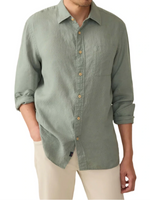 A person wearing the Faherty Laguna Linen Shirt in light green with rolled-up sleeves and beige pants.