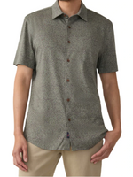 A person is wearing Faherty's Short-Sleeve Hermosa Shirt, featuring a Supima cotton fabric with a subtle geometric pattern in grayish-green tones, paired with beige pants.