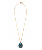 The Manami Pendant Necklace by Lizzie Fortunato is a gold-plated paperclip chain with a dark pendant, featuring blue and brown hues accented by semiprecious topaz and citrine.