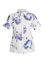The Erdem Short Sleeve Top is a white cotton poplin button-up with a pointed collar, featuring an abstract blue carnation-inspired floral print.