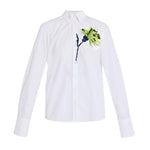 The Erdem Long Sleeve Embroidered Shirt is an oversized white cotton poplin piece adorned with green and blue floral embroidery on the upper left side.