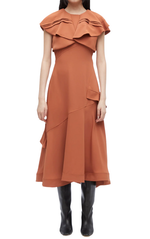 Someone wearing the 3.1 Phillip Lim Ruffle Overlay Midi Dress, a rust-colored, sleeveless piece with layered details and an asymmetric hem for a romantic vibe, paired elegantly with black knee-high boots.