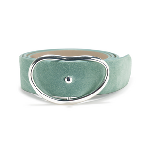 The Wide Georgia Suede Belt by Lizzie Fortunato, featuring aqua suede and a large, silver asymmetrical oval buckle, is shown rolled up against a plain white background.