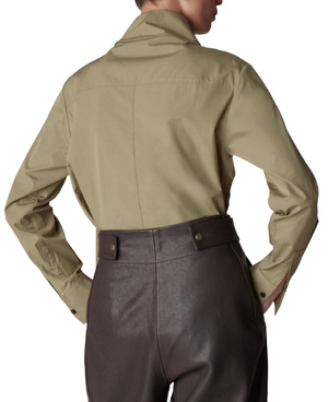 Person wearing a CO Fencer's Fluid Blouse in beige with a hint of flyaway hem and high-waisted dark brown leather pants, viewed from the back.