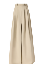 The Altuzarra Mack Skirt is a beige Italian-made high-waisted maxi skirt with elegant box pleats and a front slit.