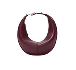 The Proenza Schouler maroon crescent-shaped Mini Slide Bag features a smooth texture, short strap with silver buckles, and a subtle monogram detail, adding elegance to its sleek design.
