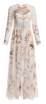The Altuzarra Sybbeline Dress is a long-sleeved sheer silk gown with a sophisticated high collar and maxi hem, adorned with intricate botanical illustrations resembling delicate tattoos.