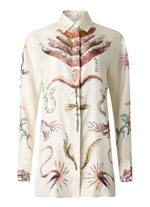 The Chika Top by Altuzarra is a long-sleeved shirt with nature-inspired illustrations and cursive text on a cream background, featuring a relaxed fit and button front closure.