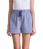 Someone wearing the Apiece Apart Surf Short—a blue-and-white vertical striped, pull-on short with a drawstring waist and side pockets—pairs well with a white top for effortless style on warm days.