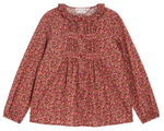 The Bonpoint Girls' Gentille Smocked and Embroidered Blouse is crafted from Liberty organic cotton with floral patterns, a ruffled neckline, and gathered front detailing in pink and red tones.