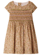 The Girls' Duchesse Smocked Dress made with Liberty Fabric by Bonpoint features short sleeves, knee-length, a gathered waist, multicolored floral print, and decorative embroidered smocking across the chest.