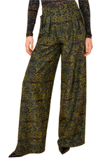 A person wearing Ulla Johnson's Charlie Silk Pant—wide-leg, high-waisted with an abstract dark green pattern—paired with a patterned long-sleeve top.