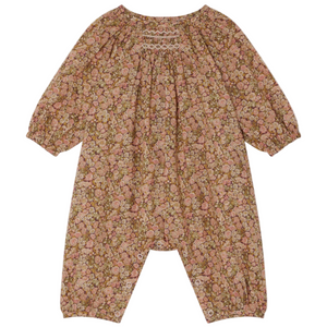 The Bonpoint Baby Girls' Jia Smocked Jumpsuit in Liberty Fabric features long sleeves, a pink and brown floral print, gathered neckline, elastic cuffs, hand-embroidered smocking, and snaps at the legs.