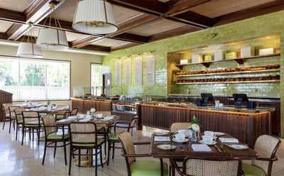 interior photo of hive bakery in cafe, with green tile walls behind the counter, and dark wood cafe tables with cane chairs