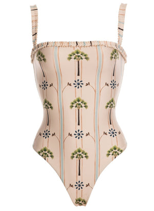 The Limon One Piece by Agua By Aguabendita is a stylish UPF 50 swimsuit crafted from recycled polyester, featuring thin ruffled straps and a palm tree print on beige.