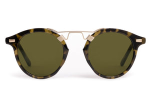 The Krewe St. Louis Tortuga 12K Sunglasses feature green lenses, rounded tortoiseshell acetate frames, and a slim 12K gold bridge—timeless style displayed against a white background.