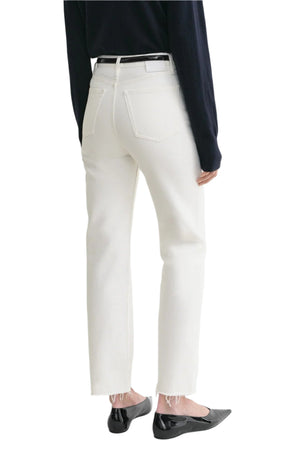 Person wearing Toteme Classic Cut Denim in white organic cotton, styled with a black belt, dark long-sleeve top, and black flats; shown from the back against a white background.