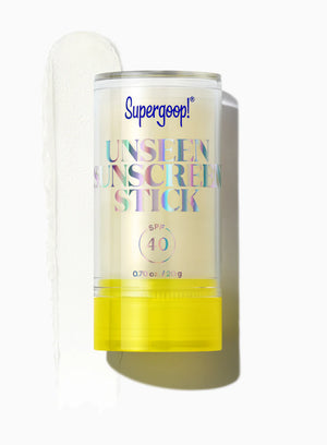 A Supergoop Unseen Sunscreen Stick SPF 40 with a yellow base is displayed beside a swipe of the clear sunscreen stick on a white background.
