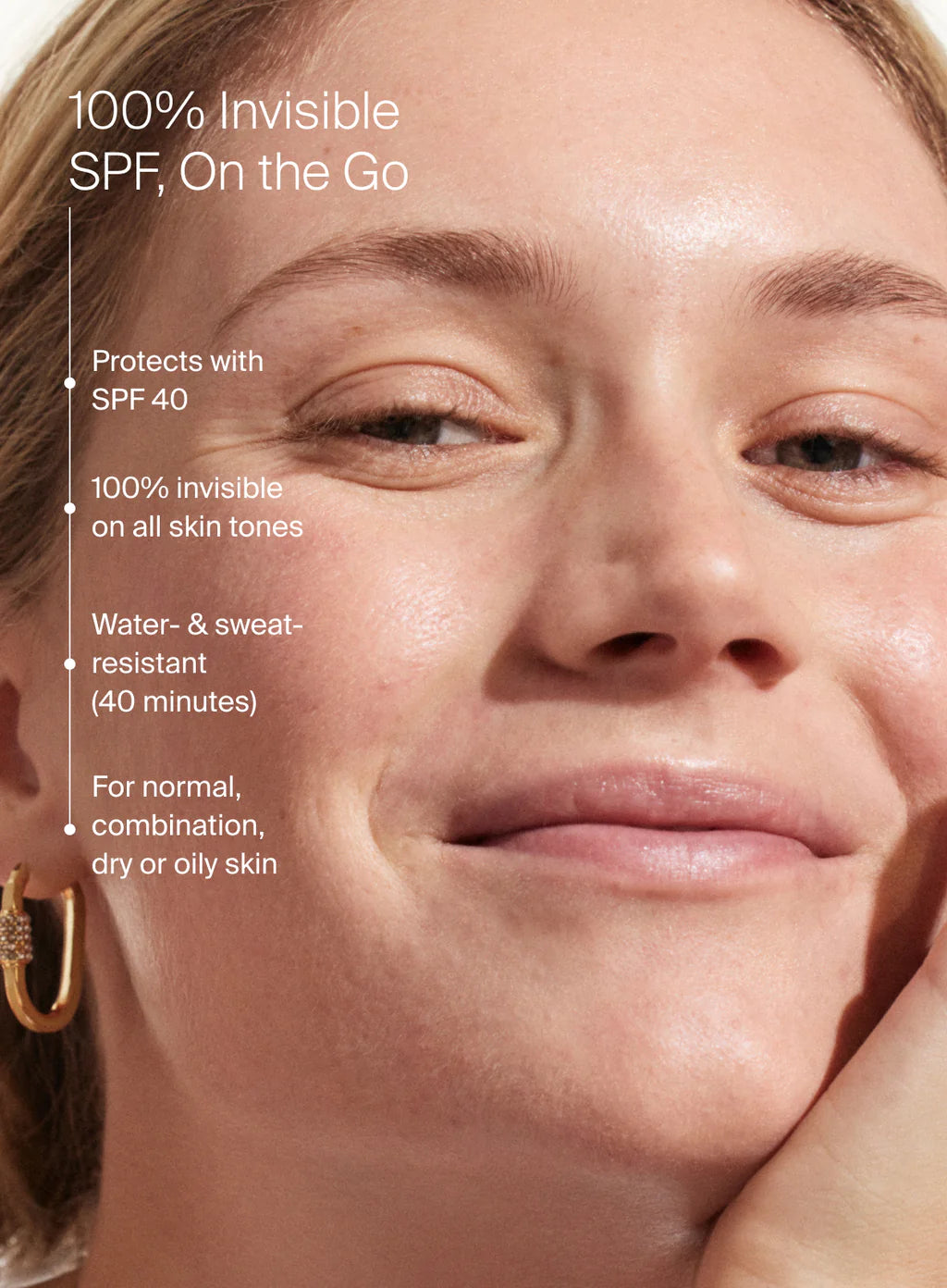 Close-up of a smiling person with minimal makeup; text overlay highlights Supergoop Unseen Sunscreen Stick SPF 40—clear, invisible, water- and sweat-resistant (40 mins), suitable for all skin tones/types, perfect over makeup.