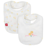 The Organic Cotton Reversible Bib from Magnetic Me provides stylish infant protection with floral designs on a white background, including yellow flowers with pink text and a pattern of small yellow flowers. Magnetic closures keep them secure.