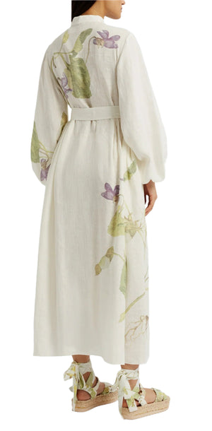 A person seen from the back wears the Erdem Long Sleeve Midi Dress With Tie Waist Detail, a white linen dress with botanical prints and long sleeves, paired with lace-up espadrille sandals.