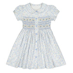 The Antoinette Baby Girls' and Girls' Violette Floral Short Puff Smocked Dress exudes French elegance with white floral patterns, short sleeves, blue buttons, and a pleated skirt adorned with light blue and yellow flowers plus exquisite blue accent stitching on the bodice.
