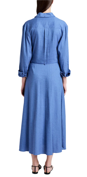 Someone is wearing the Lato Wrap Dress Linen Slub by Proenza Schouler White Label with black sandals, featuring a long-sleeve, button-up blue design and rolled cuffs for a classic shirtdress silhouette.