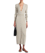 A person wearing a Proenza Schouler White Label Ivanna Dress Micro Check featuring a long, patterned knit with a deep V-neck and slim silhouette, holding a black handbag and wearing black sandals.