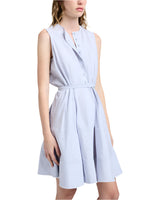 A woman stands against a plain background wearing the Proenza Schouler White Label Kenzie Dress Linen, a sleeveless light blue button-front dress with a belted waist and fit-and-flare silhouette.