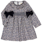 The Kidiwi Baby Girls' and Girls' Adriana Corduroy Bows Smocked Dress features a blue and white floral pattern, handmade smocking on the chest, and two black velvet bows at the waist for a charming look.