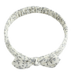 The Rylee & Cru Baby Bow Headband features a soft white band with a gray leaf pattern, a small bow, and a comfy scrunchy elastic back for babies.