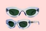 Two pairs of oval, translucent light blue Thierry Lasry Jazz Sunglasses with dark green lenses are displayed against a pale pink background.