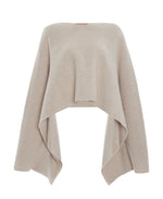 The Altuzarra Trip Sweater is an off-the-shoulder beige knit top featuring a luxurious cashmere wool-blend with a slashed neckline and draped, asymmetrical hem.